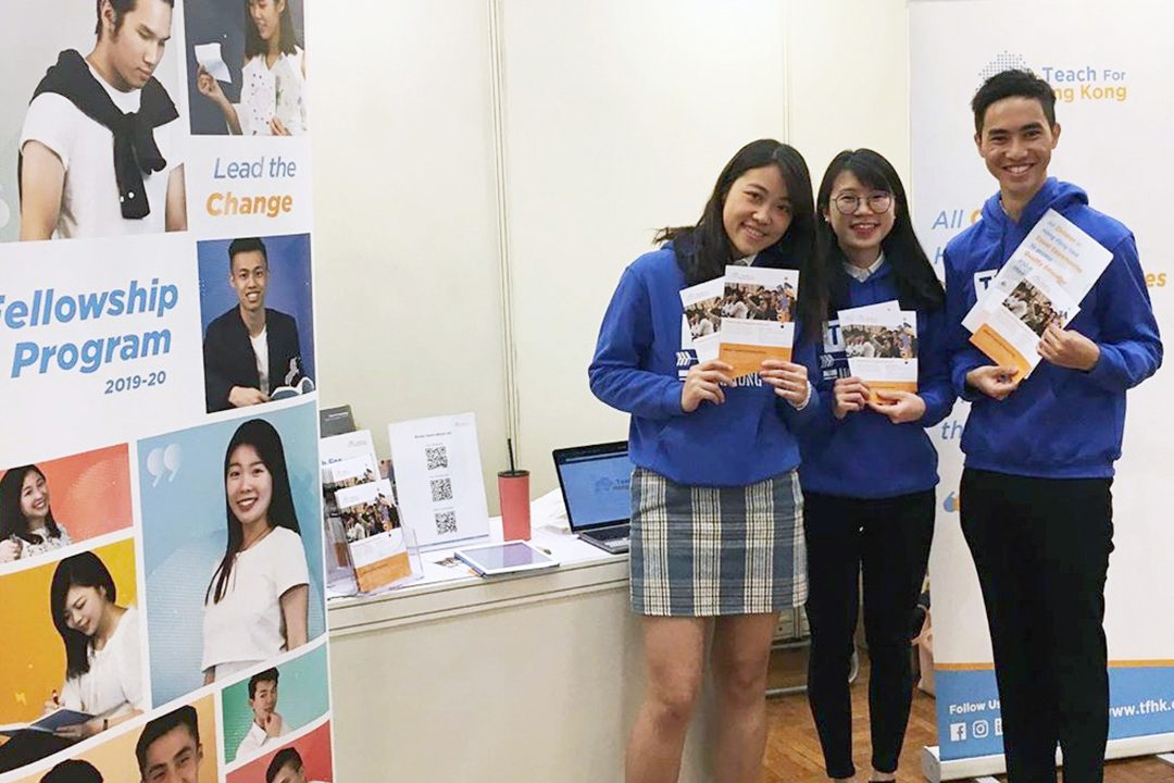 Teach For Hong Kong staff posing with a pull-up banner at a recruitment booth